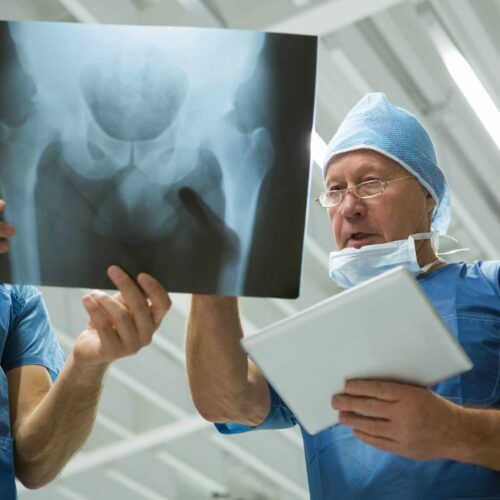 Male surgeons holding digital tablet while discussing x-ray in hospital